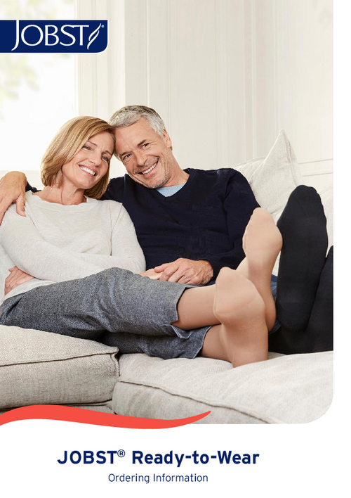 Man and women sat on the sofa with the legs up and heads close together looking at their feet and smiling